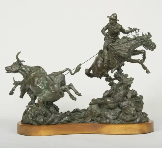 Bronze equestrian sculpture showing riders on galloping horses atop a wooden pedestal with ropes trailing from the figures.