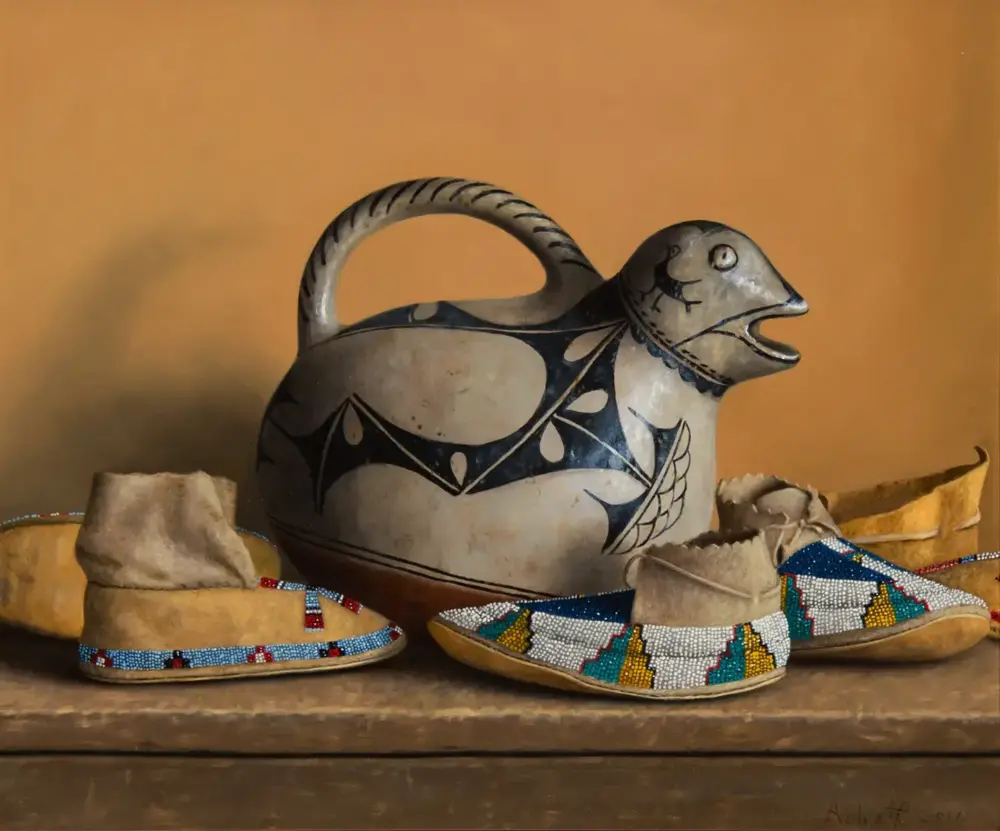 Ceramic bird-shaped pitcher with a curved handle and black geometric designs, set among beaded moccasin footwear on a wooden surface.
