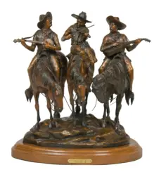 Bronze sculpture of three cowboys on horseback playing string instruments, mounted on a wooden base.