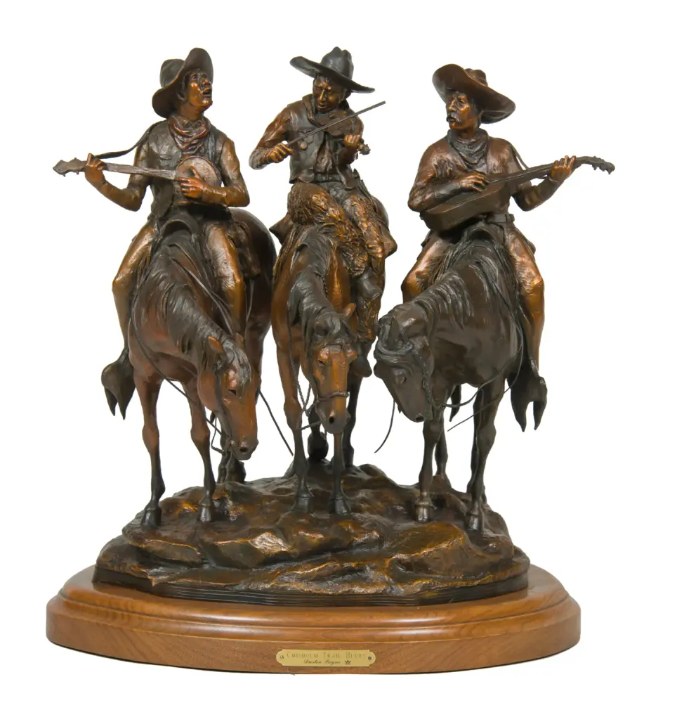 Bronze sculpture of three cowboys on horseback playing string instruments, mounted on a wooden base.