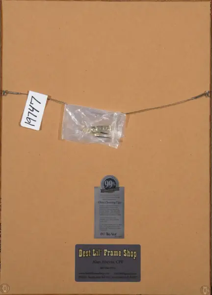 Back of a framed piece showing a hanging wire, small hardware bag, a tag, and a Best Lil' Frame Shop sticker.