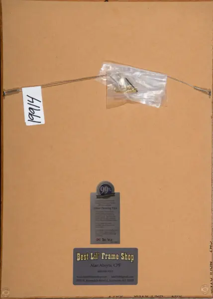 Back of a wooden frame showing crossbar hanging wires, a small plastic bag with hardware, a handwritten tag, and a 'Best Lil' Frame Shop' label at the bottom.