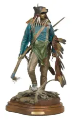 Detailed sculpture of a tribal hunter wearing a bear head headdress, turquoise robes, and bone necklace, standing on a rocky wooden base.