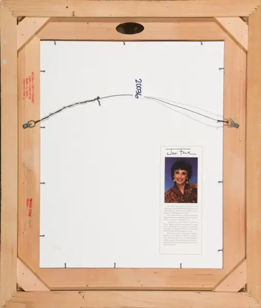 Back of framed artwork showing a hanging wire, wooden frame, and a small biography card with a photo of a woman.