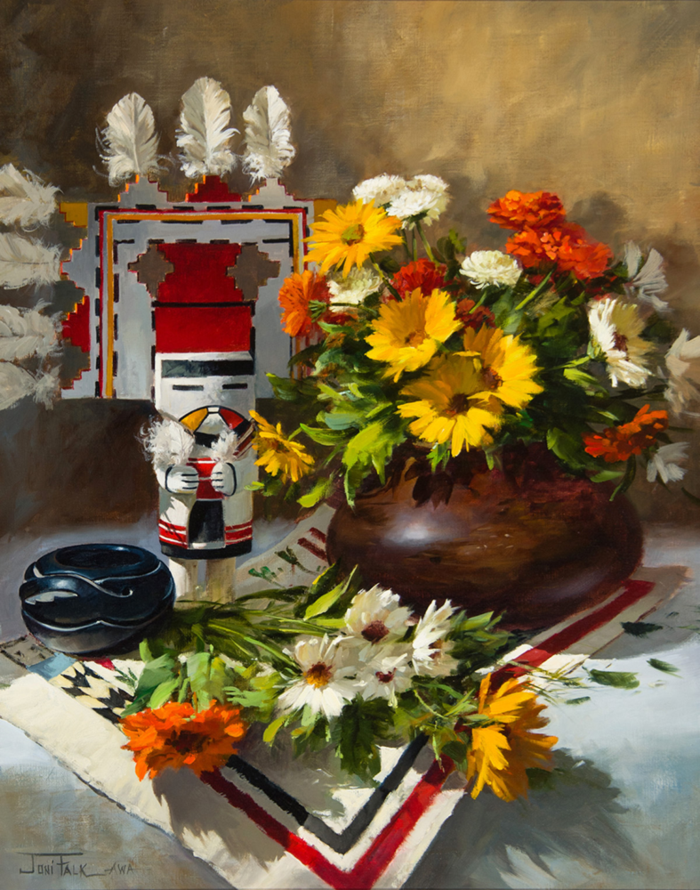 Vibrant bouquet in a dark vase with a geometric red-gray sculpture and a black dish on a checked tablecloth.