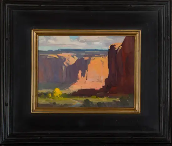 Oil painting of a canyon landscape with tall red cliffs, sunlit orange rocks, and a distant valley under a cloudy sky, in a black frame with a gold inner border.