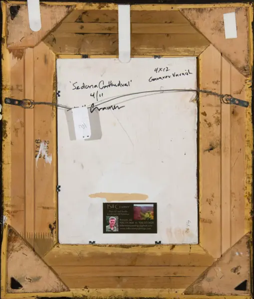 Back of a framed painting on a wooden stretcher with a hanging wire, handwritten notes and a small business card at the bottom.