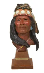 Clay bust sculpture of a Native American chief with a feathered headdress on a wooden pedestal, plaque reads 'White Mountain Chief'