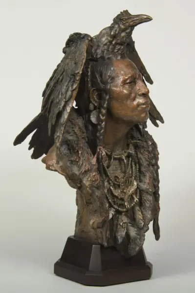 Bronze bust of a woman with a dramatic feathered wing headdress and beaded necklace on a dark pedestal