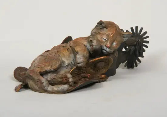 Abstract bronze sculpture of a reclining figure with a sunburst-like wheel at the far end