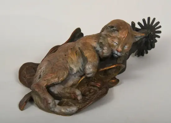 Bronze sculpture of a reclining dog with a textured, reddish-brown patina on a base.