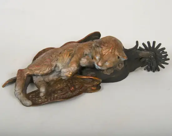 Bronze sculpture of a sleeping dog lying on its side on a dark base with a spiky black abstract form nearby.