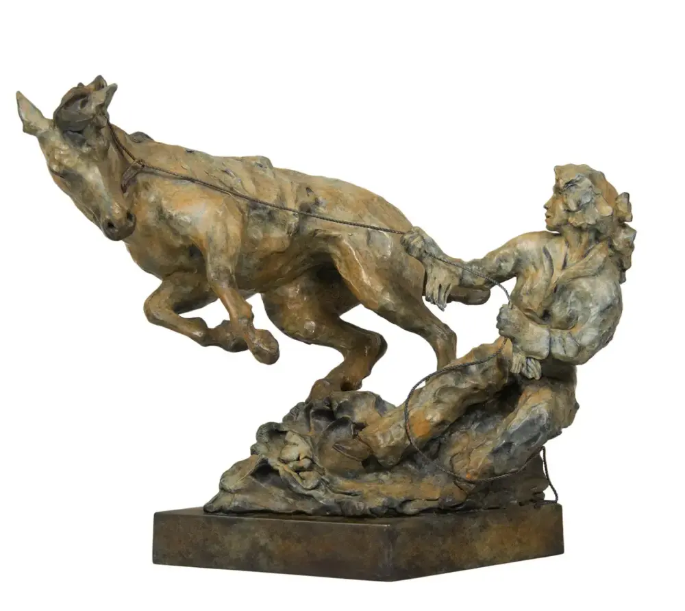 Bronze sculpture of a man leading a bucking horse with a rope on a rocky base.