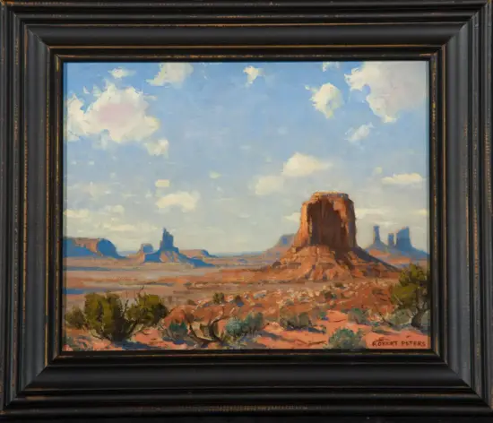 Framed landscape painting of a desert scene with red rock buttes and a bright blue sky, signed Robert Peters in the lower right corner.