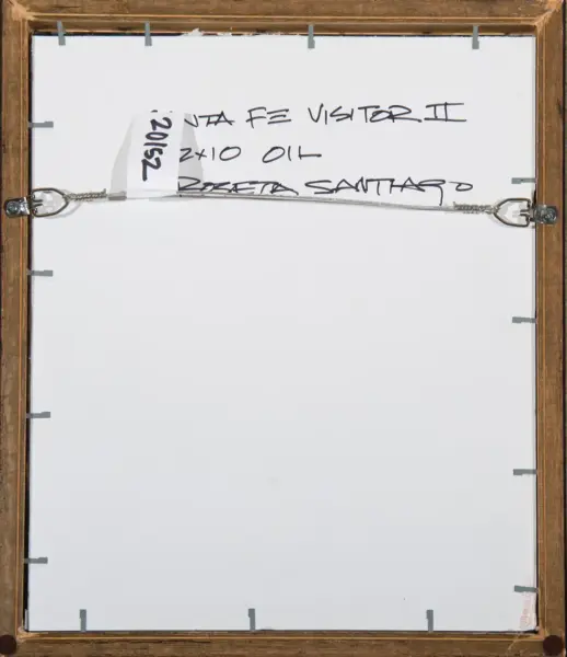 Back of a framed painting showing a metal hanging wire stretched across the frame with a white backing and a small numbered tag on the left side.