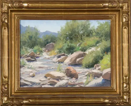 Impressionist landscape of a rocky river with green trees and distant mountains, in a gold ornate frame.