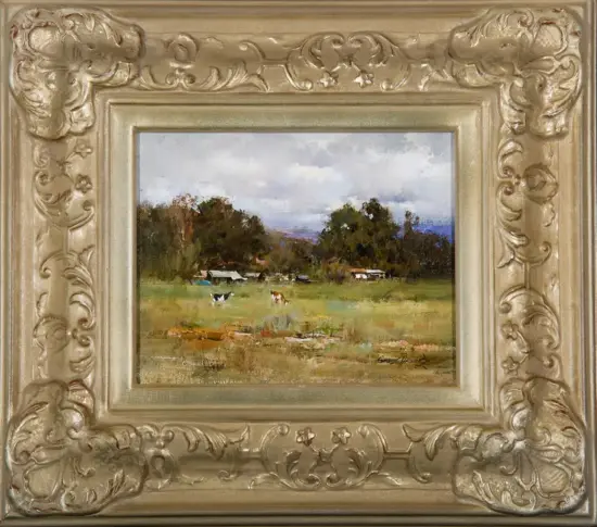 Oil painting of a countryside field with cows, small houses, and trees under a cloudy sky, in an ornate gold frame.