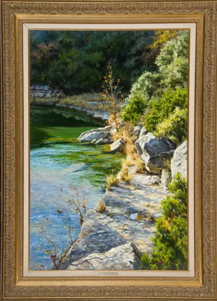 Framed landscape painting of a rocky lakeshore with green water and dense trees in the background