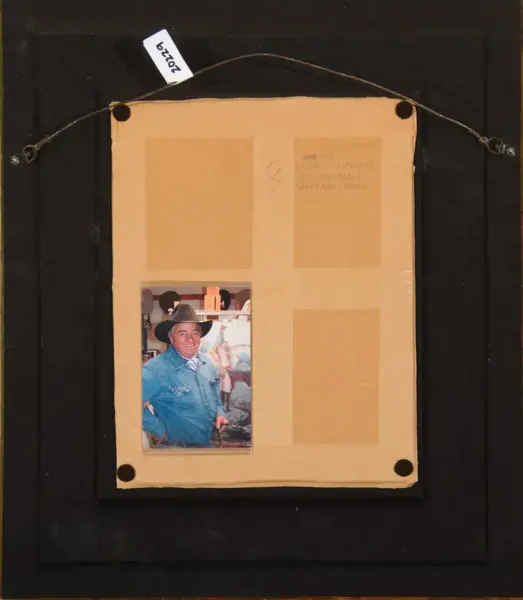 Back view of a framed photo display: a beige mat with a single portrait of a smiling man in a denim shirt and cowboy hat on the bottom left.