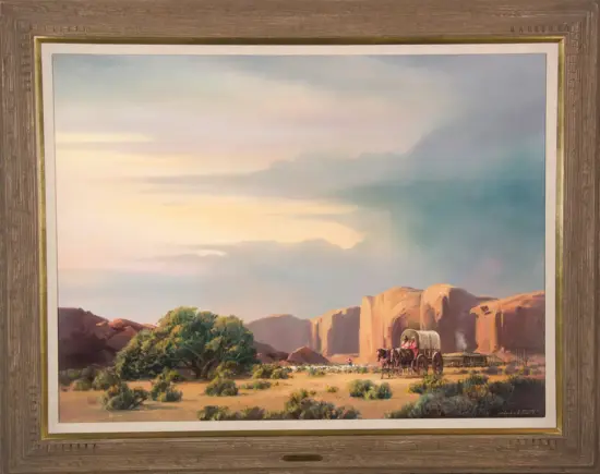 Oil painting of a wagon pulled by horses crossing a desert with cliffs and sparse shrubs at dusk, in a wood frame.