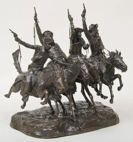 Bronze sculpture of four cowboys on galloping horses, guns raised in a coordinated charge on a rugged base.